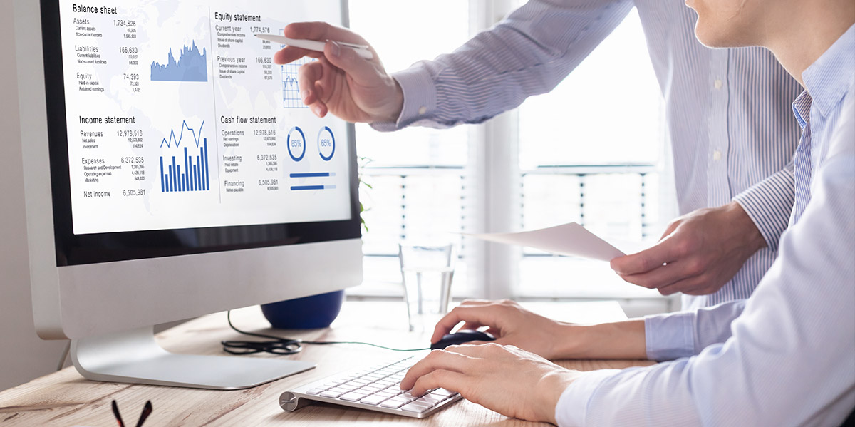 two coworkers reviewing financial report on a computer screen