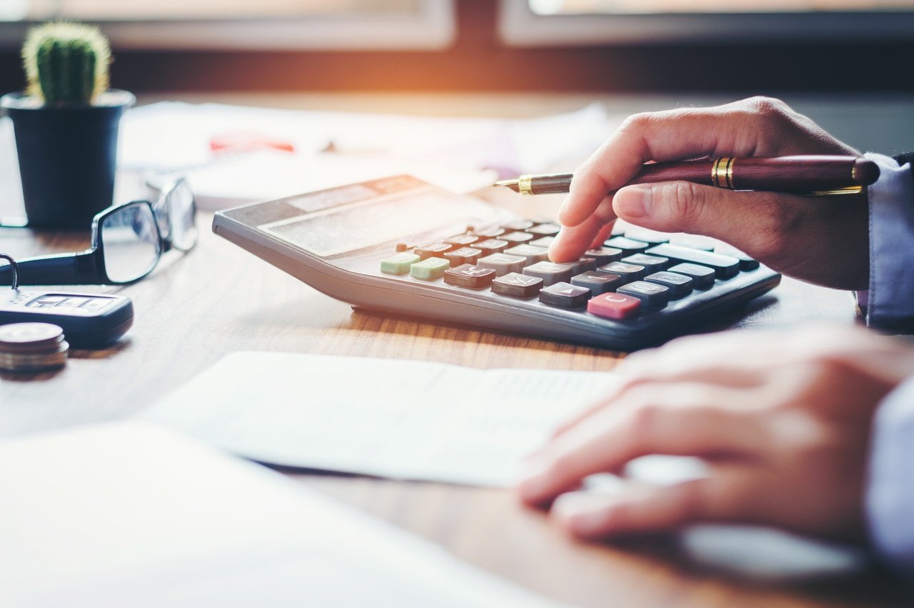 close up of man using calculator with a pen in his hand