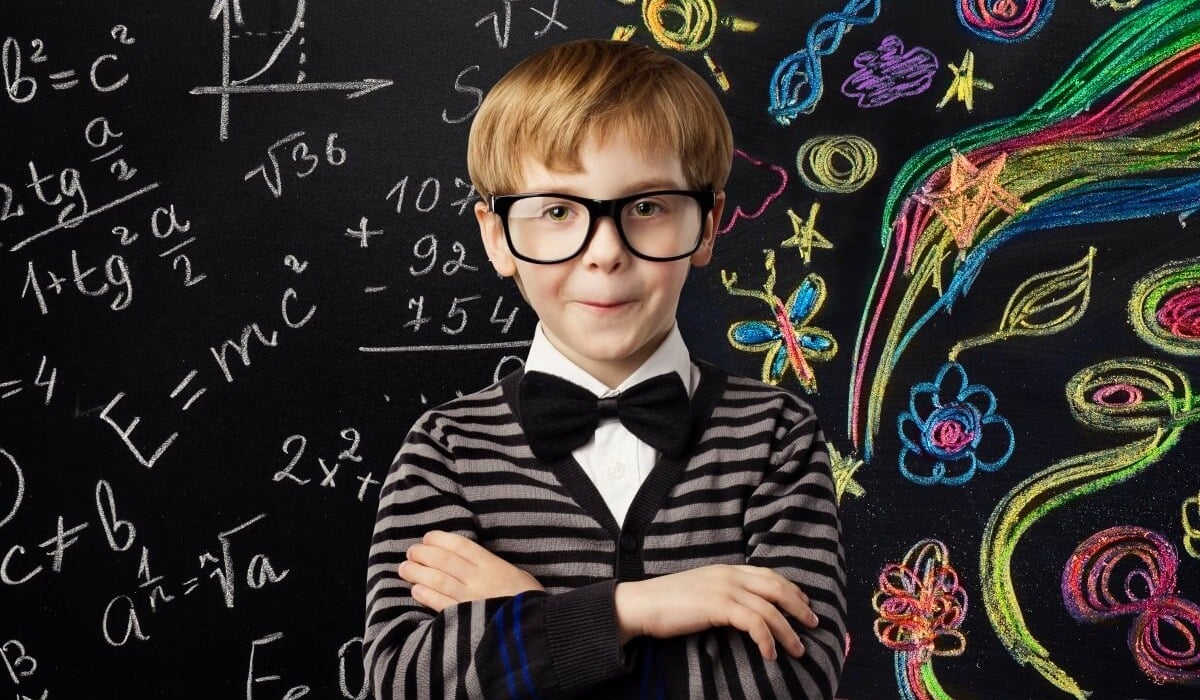 bespeckled child standing in front of a chalk board filled with equations and doodles